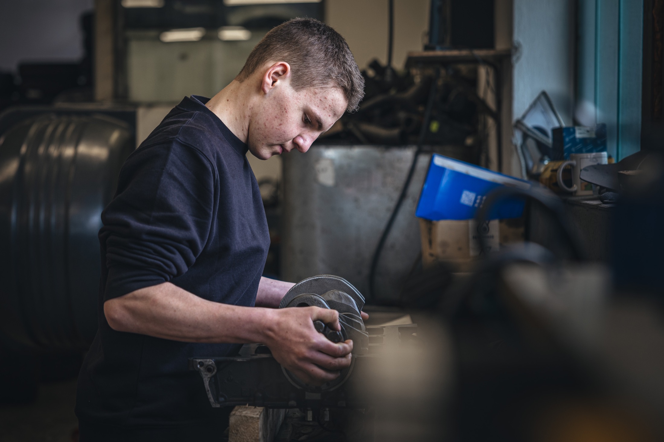 Mechaniker hält ein Bauteil zur Qualitätskontrolle